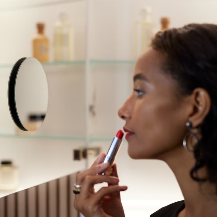 Женщина наносит макияж перед зеркалом Женщина наносит макияж перед зеркалом